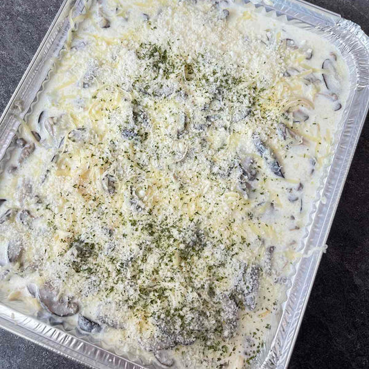 Mushroom dish with cheese in a foil container on a dark surface